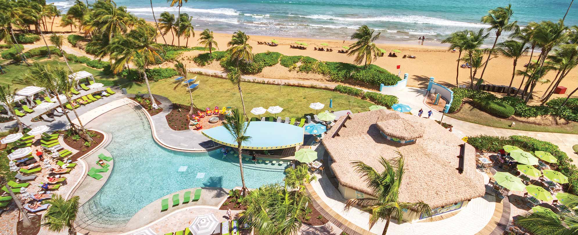 Birds-eye-view of the ocean and pool, with a boat-shaped swim-up bar, at Margaritaville Vacation Club by Wyndham - Rio Mar.